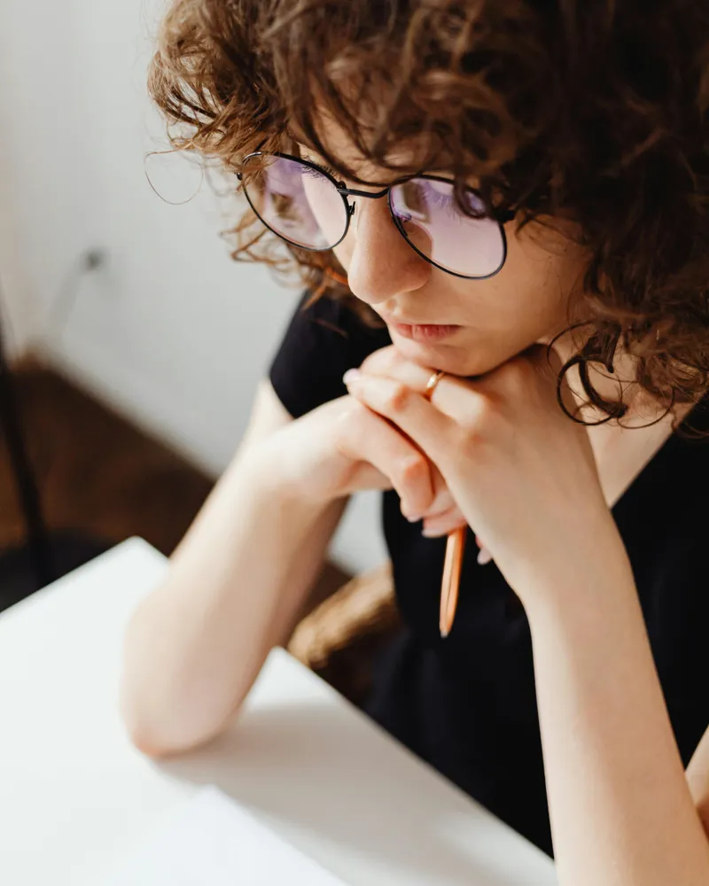 Woman with hands on chin in deep thought, reflecting on mental clarity and focus
