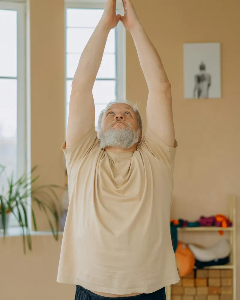 Elderly man practising yoga indoors for active wellbeing