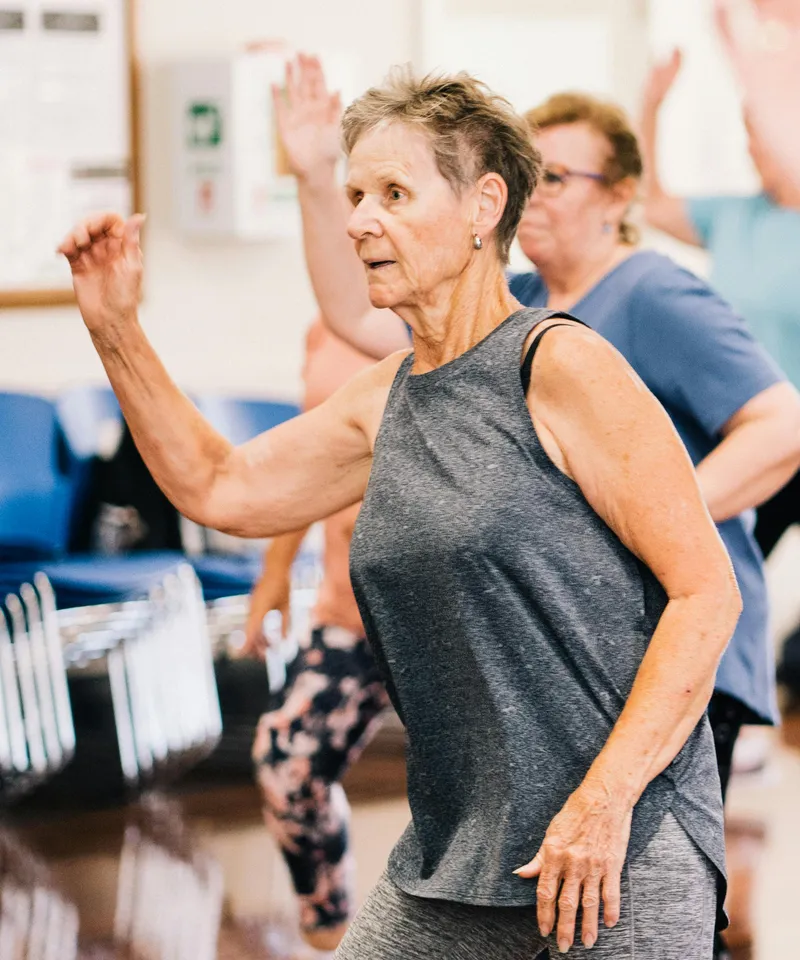 Elderly woman in a group fitness session promoting active ageing and vitality