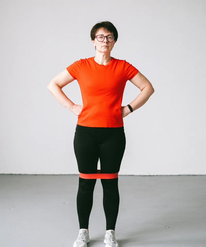 Woman doing resistance band rehabilitation exercises indoors as part of injury recovery care